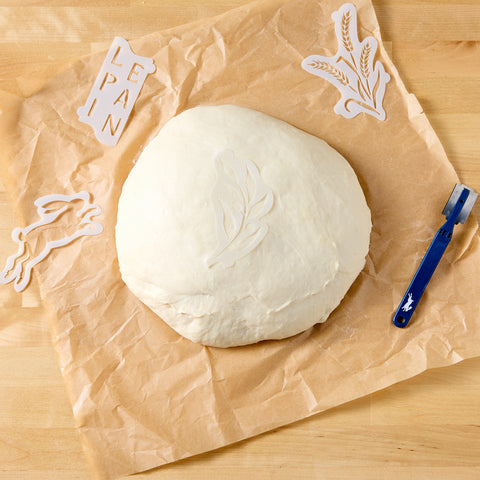 Provence bread stencils around round dough on parchment: wheat and 'PAIN' pieces