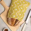Waxed bread storage bag with leafy print, fold-over cover over loaf, yellow fabric