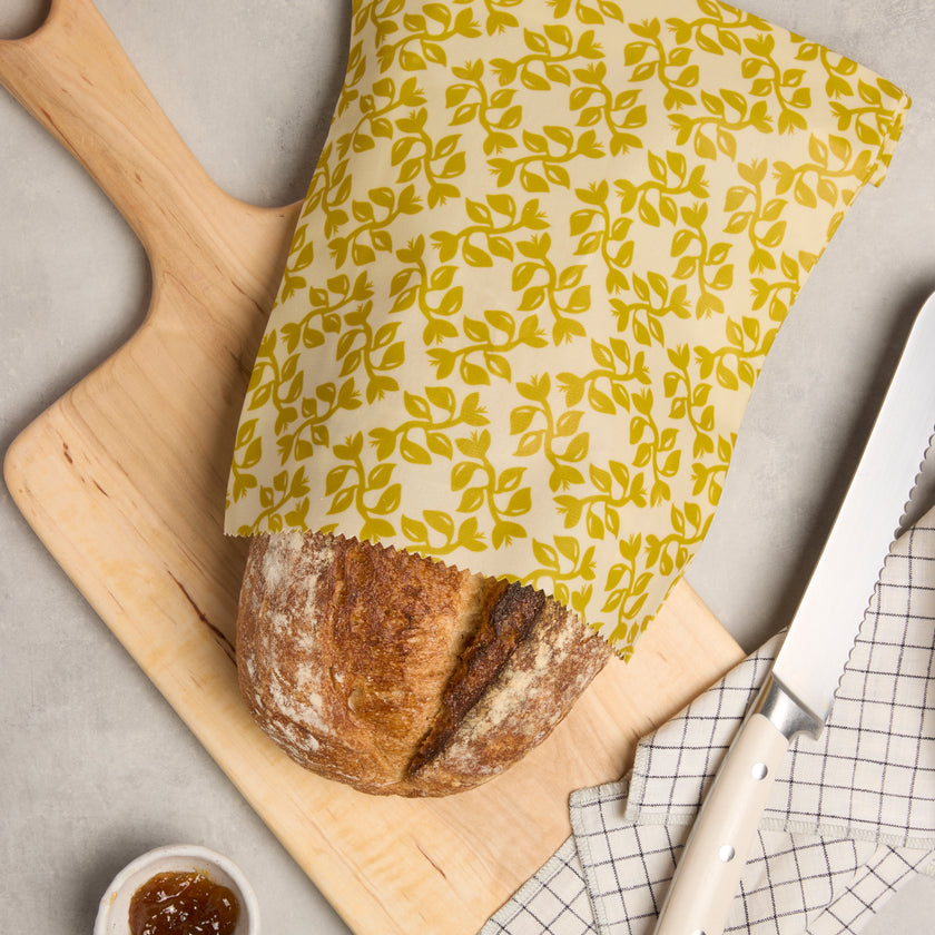 Waxed bread storage bag with leafy print, fold-over cover over loaf, yellow fabric