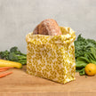 Yellow waxed pantry bag with leafy pattern, fold-over top, holds a round loaf
