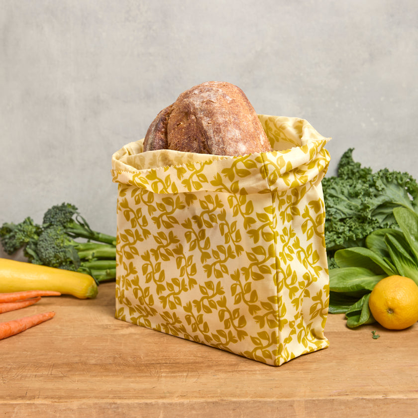 Yellow waxed pantry bag with leafy pattern, fold-over top, holds a round loaf